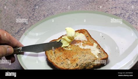 Buttering toast. Hand holding knife spreading butter onto a piece of toast Stock Photo - Alamy