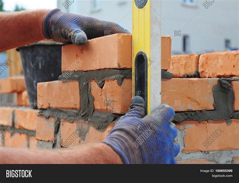 Bricklayer Using a Spirit Level to Check New Red Brick Wall Outdoor ...