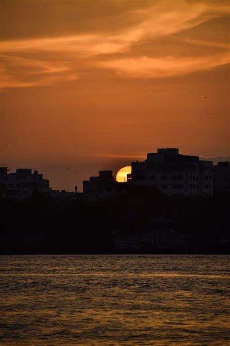 Town Silhouette behind Water at Sunset · Free Stock Photo