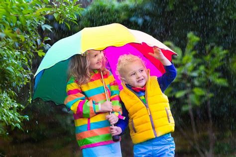 Kids Playing in the Rain Under Colorful Umbrella Stock Photo - Image of ...