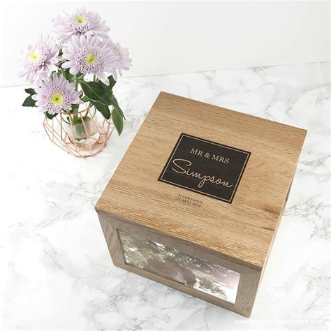 a wooden box sitting on top of a marble counter next to a vase with flowers