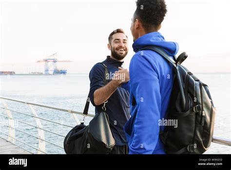 Two attractive smiling young healthy sportsmen outdoors at the beach, shaking hands Stock Photo ...