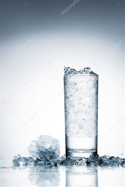 vaso de agua fría con hielo sobre superficie reflectante sobre blanco 2022