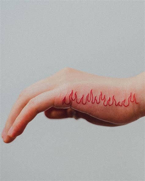 a person's hand with a red flame tattoo on the left side of their arm