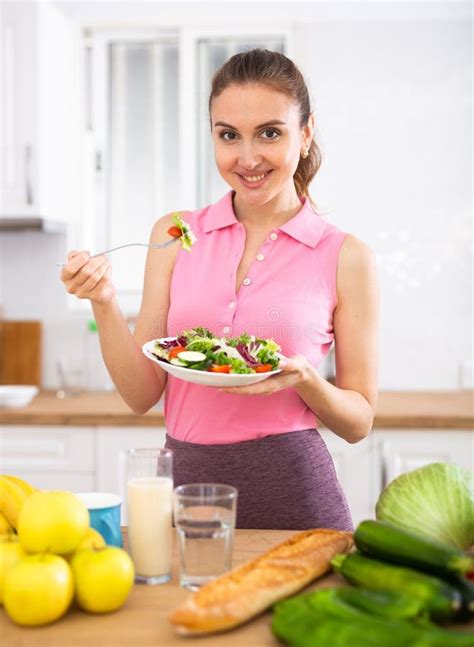 Vegeterian Woman Standing at Table in Kitchen and Eating Vegetable ...
