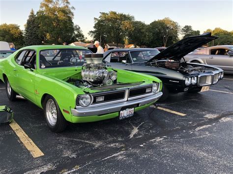 two green cars parked next to each other in a parking lot with people ...