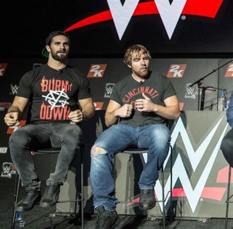 three men are sitting on chairs in front of a microphone and one man is ...