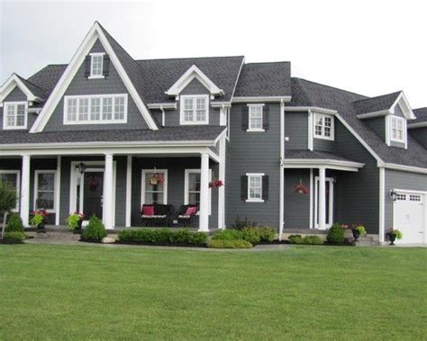 a large gray house with white trim on the front and side windows is ...