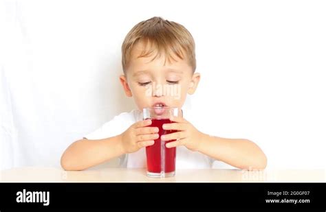 A child drinks juice from a glass beaker on a white background, after which he Stock Video ...