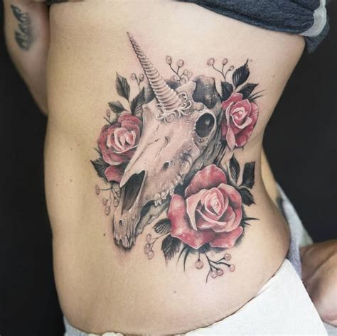 a woman's stomach with roses and an animal skull tattoo on the bottom side