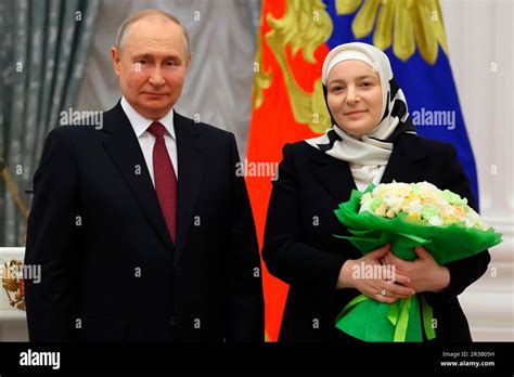 Russian President Vladimir Putin, left, awards large family mother Medni Kadyrova, wife of ...