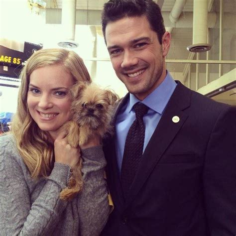 a man in a suit and tie holding a small dog with his arm around a woman ...