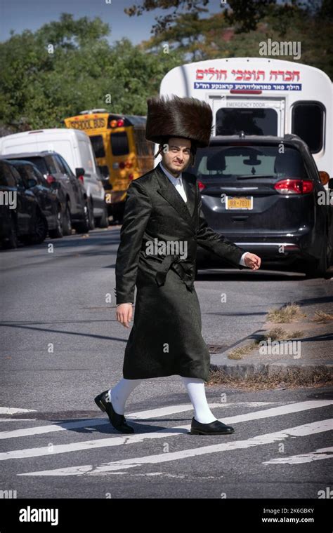 A Hasidic man, wearing a Shtreimel fur hat and high white stockings, crosses a street in ...