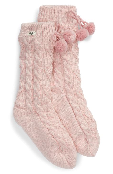 Chunky cable-knit yarn textures the exterior of these cozy crew socks enhanced by fuzzy pompom ...