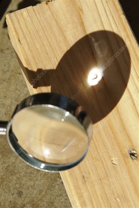 Magnifying glass focusing sun light - Stock Image - C021/9906 - Science Photo Library