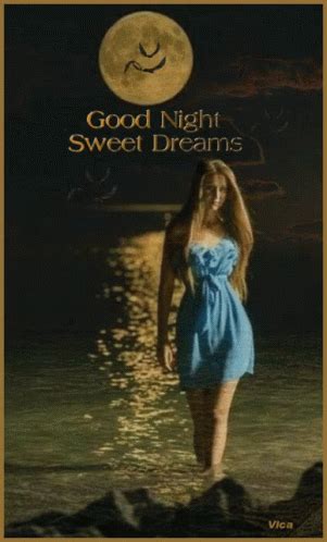 a woman in a blue dress walking into the ocean at night with a full moon behind her