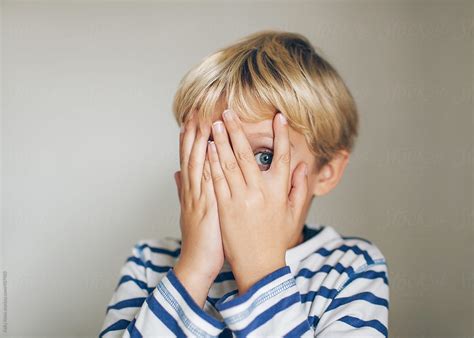 Scared Child Peeking Between His Fingers | Stocksy United