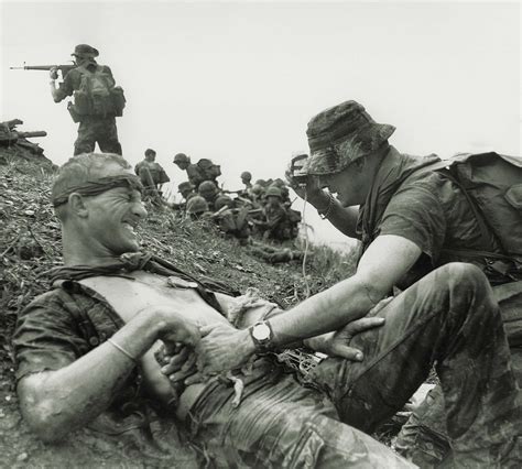 A medic attends a wounded Special Forces soldier as South Vietnamese and Montagnard troops ...