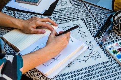 Premium Photo | Caucasian female hands on a table drawing sketches on a white sheet with a black ...