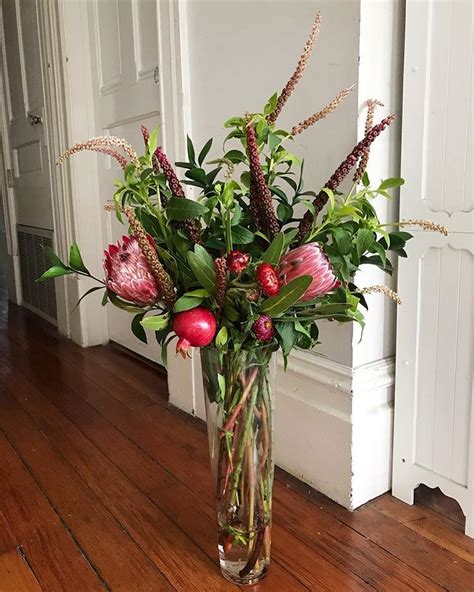 holiday flower arrangement made with pomegranate, straw flower, protea, pokeberry, ruscus ...