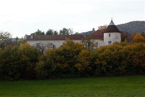 a white building sitting next to a lush green field with trees in front of it