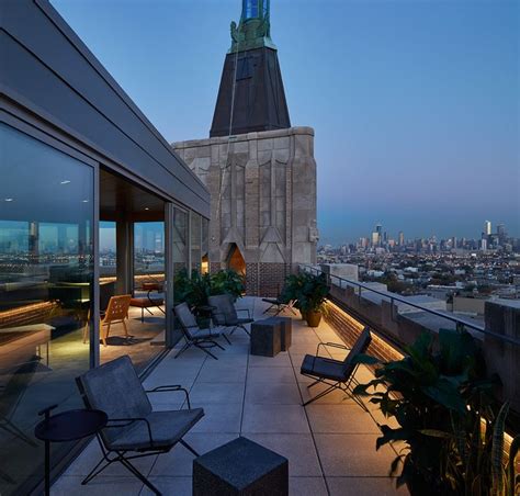 an outdoor patio with chairs, tables and plants on the top of a tall building