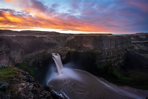 the sun is setting over a large waterfall