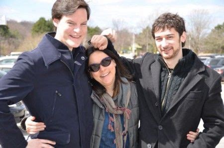 two men and a woman standing next to each other in front of a parking lot