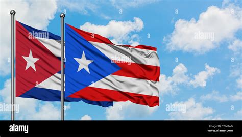 Cuba and Puerto Rico flag waving in the wind against white cloudy blue ...