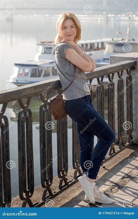 Young Blonde Woman Enjoying City View from the Bridge. Lovely Woman Spending Time on the River ...