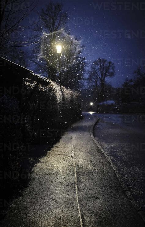 Street light illuminating empty sidewalk at winter night stock photo