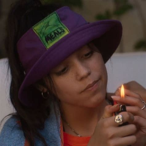 a woman wearing a purple hat and holding a lighter