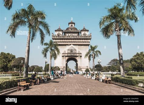 Ancient beautiful arch in the park in Laos. Walking street with palms ...