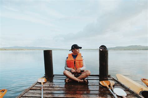 Man Wearing Life Vest While Sitting On The Dock · Free Stock Photo