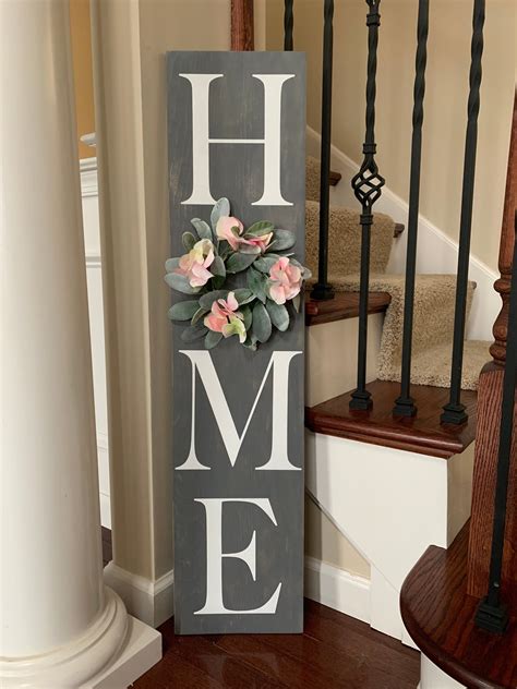 a wooden sign that says home with flowers on it next to some banisters