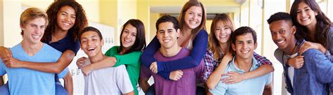 Group Of High School Students Giving Piggybacks In Corridor Smiling - LiFT Learning™