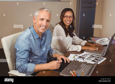 Creative business people working with laptop at desk in office Stock Photo - Alamy