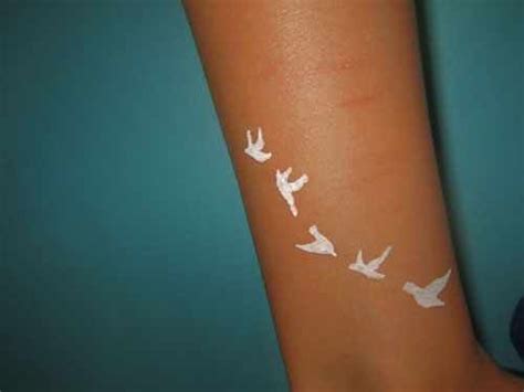 a white tattoo on the arm of a woman with birds painted on it's arm