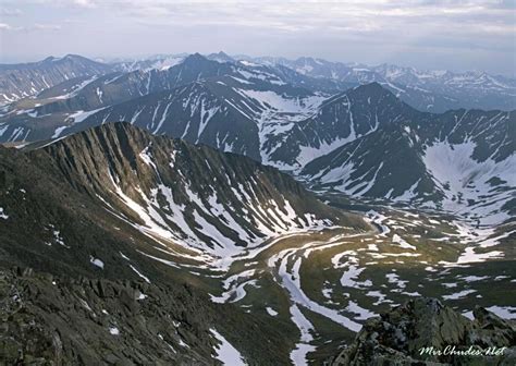 the mountains are covered in snow and have ridges that lead into the distance with white patches ...