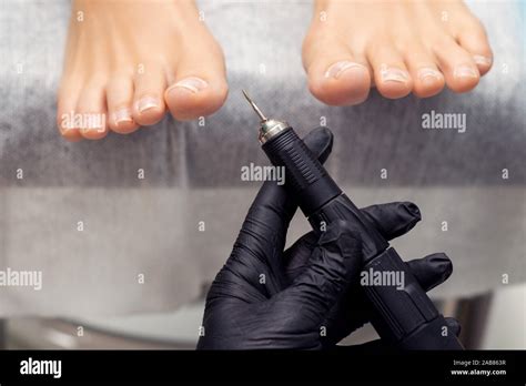 Professional pedicure technician holds special electric machine for ...