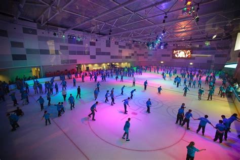 people skating on an ice rink with colored lights in the ceiling and around them are skateboarding