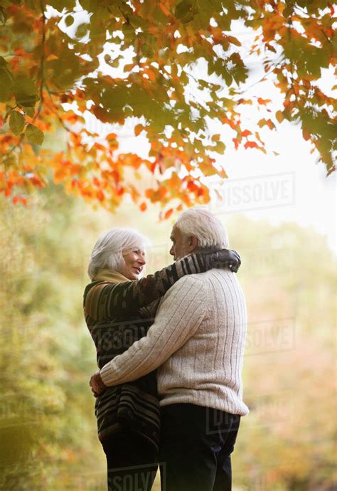 Older couple hugging in park - Stock Photo - Dissolve