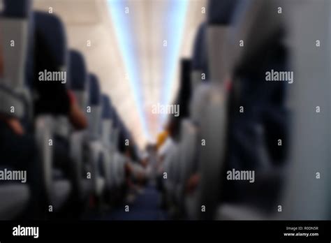 passenger sit on seat in airplane. aisle in aeroplane interior. blurry ...