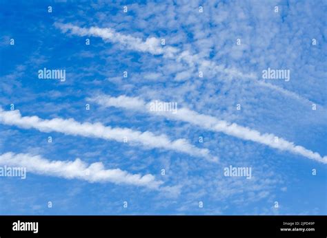 Condensation trails of aircraft and clouds in the blue sky Stock Photo - Alamy