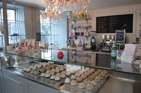 a bakery with lots of cupcakes on display in front of the counter and chandelier