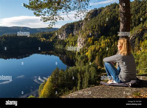 Beautiful young woman contemplating nature on top of a cliff overlooking a beautiful lake Stock ...