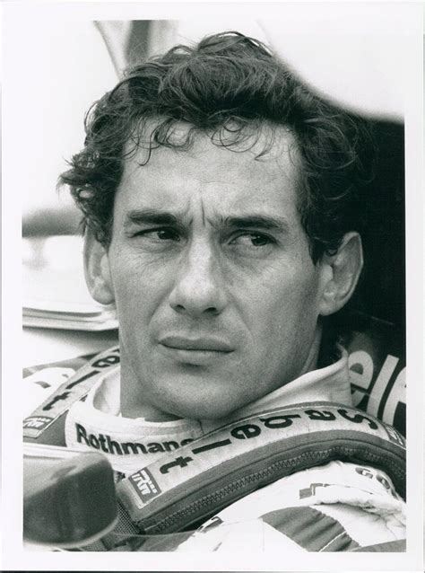 a black and white photo of a man in a racing suit looking at the camera