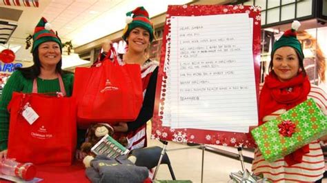 three women dressed in christmas themed clothing standing next to a sign with writing on it