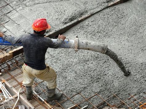 Group of construction workers pouring wet concrete using concrete hose from concrete pump into ...