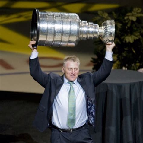 a man in a suit holding up a silver trophy over his head with both hands